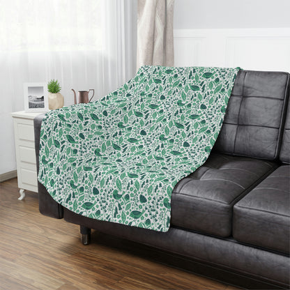 green plush throw blanket lying on a bed, floral bird blanket used in bedroom decor, green accent blanket for couch or bed