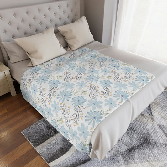 light blue floral throw blanket on a bed, blue flowers on a plush throw blanket in a bedroom