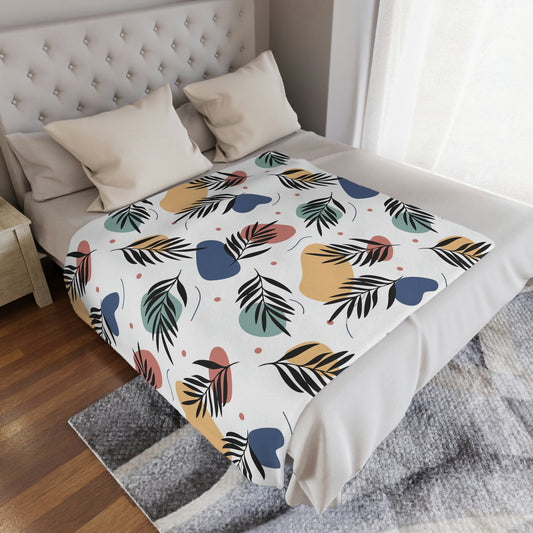 Palm leaves throw blanket lying on a bed, floral blanket with palm leaves on it decorating a bedroom, plush palm leaves throw blanket lying next to pillows on a bed