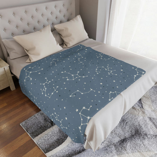 blue constellation space theme blanket lying on a bed, starry pattern baby blanket for nursery on a bed, blue blanket in a space theme playroom 