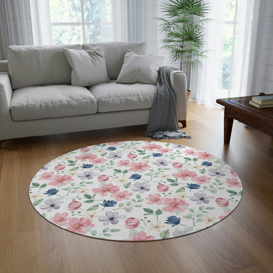 white area rug with pink and blue and purple flowers, blue floral pattern, pink and purple flower pattern on a floor rug sitting on a hardwood floor in the living room, couch with pillows on it
