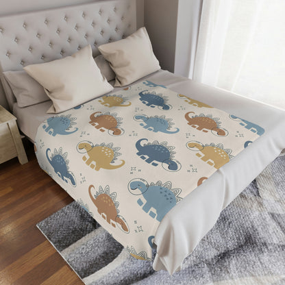 space dinosaur blanket lying in a nursery, blue and yellow dinosaur baby blanket lying on a bed, space theme baby blanket with dinosaurs on it in a playroom