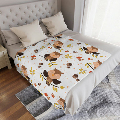 owl baby blanket in a woodland theme nursery, woodland animal plush blanket lying on a bed in a kids playroom, owl throw blanket next to pillows on a woodland animal crib