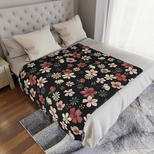 black blanket with pink and red flowers, red and pink floral throw blanket lying on a bed or couch, pink flower pattern on a blanket, red floral print on a throw lying on a bed